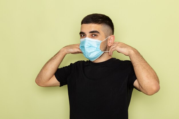 Front view young male in black t-shirt wearing sterile mask on green