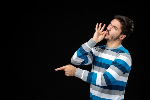 Foto gratuita vista frontale giovane maschio in maglia a righe blu sul muro nero