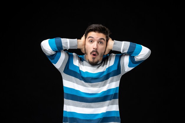 Front view young male in blue striped jersey on black wall