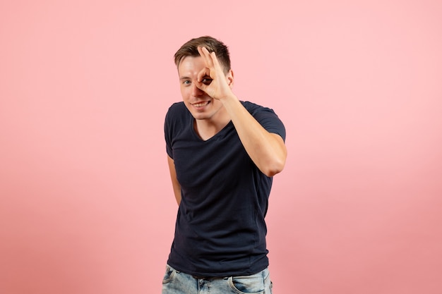 Front view young male in blue t-shirt posing on pink background emotions color model human male