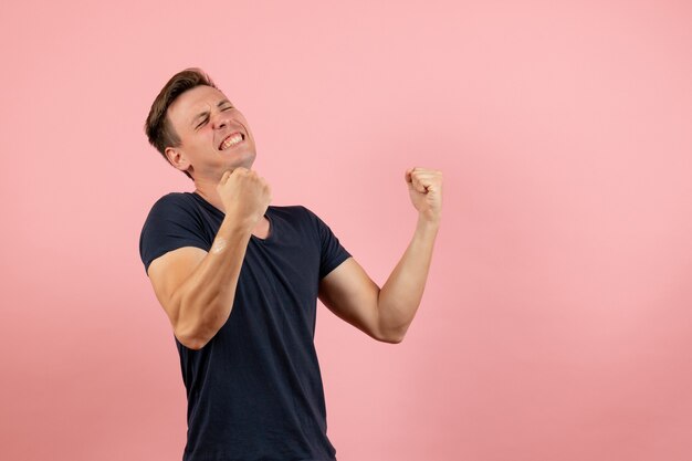 Front view young male in blue t-shirt posing and rejoicing on pink background man model emotion color male