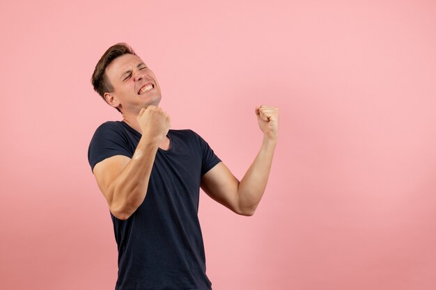 Вид спереди молодой мужчина в синей футболке позирует и радуется на розовом фоне мужчина модель эмоция цвет мужчина