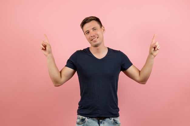 Вид спереди молодой мужчина в синей футболке позирует с улыбкой на розовом фоне цветовая модель мужских человеческих эмоций