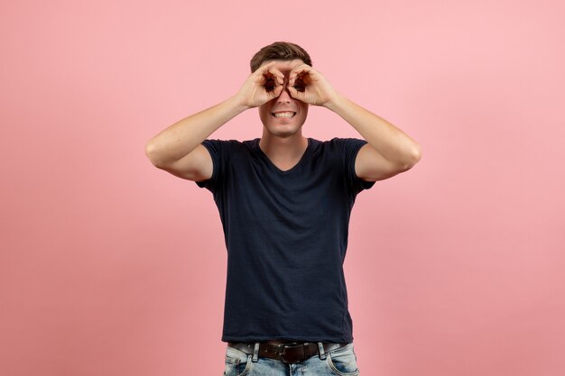 Вид спереди молодой мужчина в синей футболке позирует с улыбкой на розовом фоне мужчина модель эмоция цвет мужчины