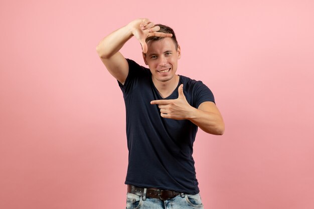 Front view young male in blue t-shirt showing picture sign on pink background male emotion color model human