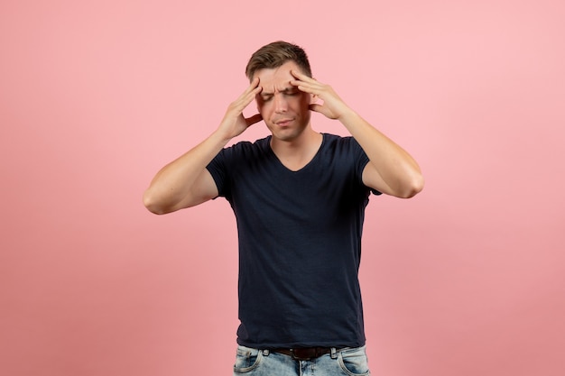 분홍색 배경에 두통을 앓고 파란색 티셔츠에 전면보기 젊은 남성 남자 모델 감정 색상 남성