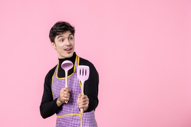 분홍색 배경 식사 수평 작업 반죽 요리 요리 색상 음식 유니폼에 숟가락을 들고 케이프에 젊은 남성 전면보기