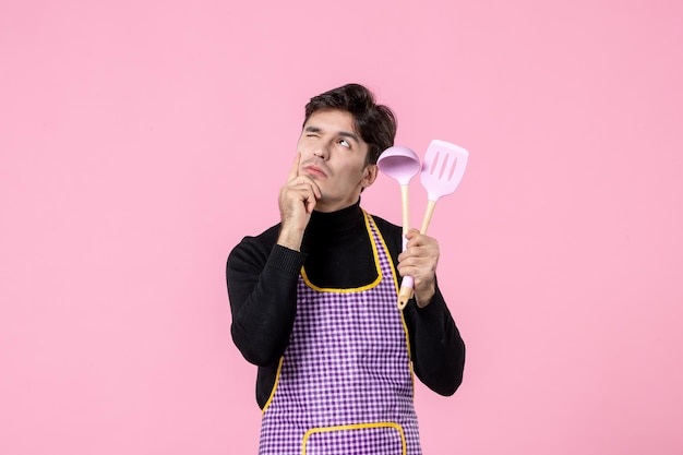 Front view young male in cape holding spoons on pink