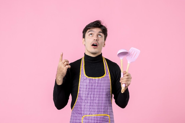 Front view young male in cape holding spoons on pink