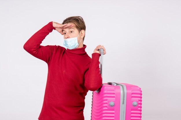 Front view of young male carrying pink bag on white wall