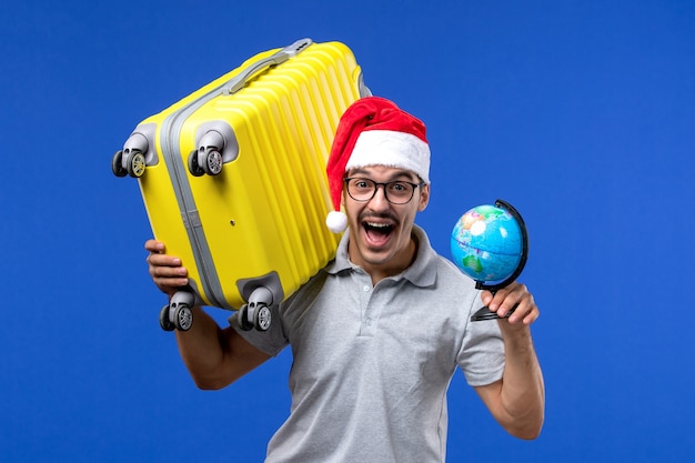 Free photo front view young male carrying yellow bag on blue desk plane vacation trip male