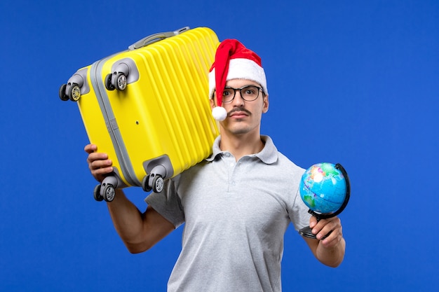 Front view young male carrying yellow bag on blue wall plane vacation trip male