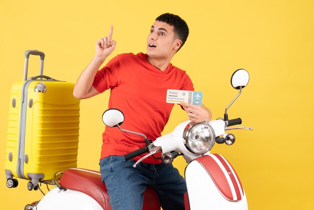 Front view young male in casual clothes on moped holding plane ticket