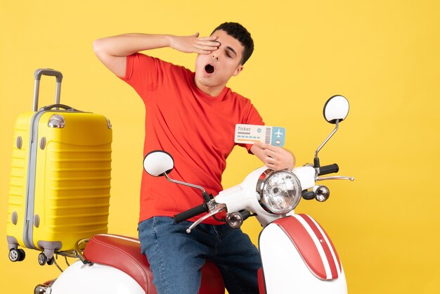 Front view young male in casual clothes on moped holding travel ticket