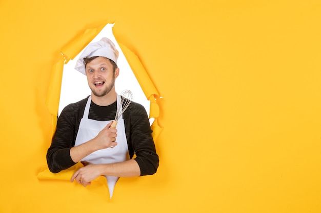 Free photo front view young male cook in white cape holding whisk on the yellow background photo food man cuisine kitchen job color white