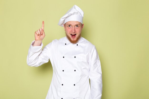 A front view young male cook in white cook suit white head cap posing