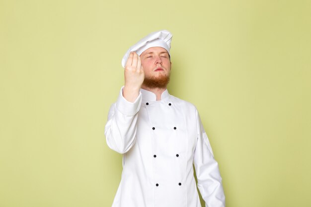 A front view young male cook in white cook suit white head cap tasty sign