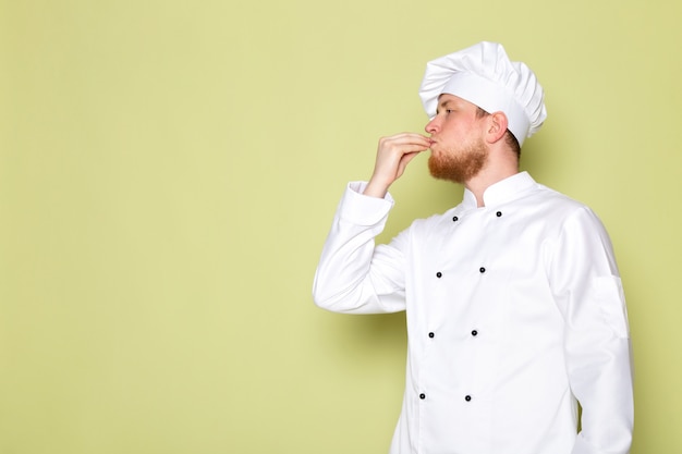 A front view young male cook in white cook suit white head cap