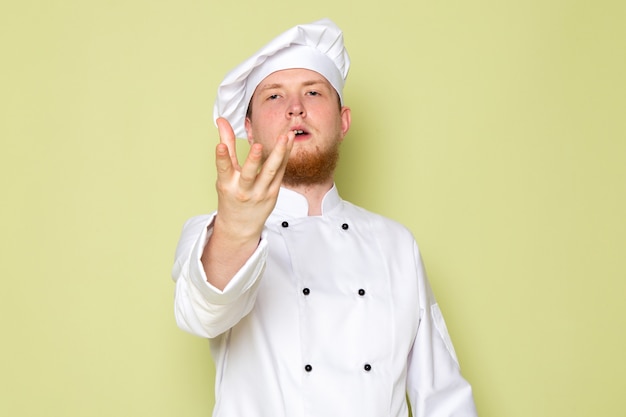 Вид спереди молодой мужской повар в белом костюме повара белая шапка