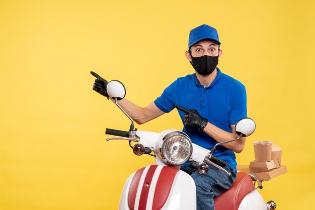 黄色の背景にマスクで自転車の正面図若い男性宅配便