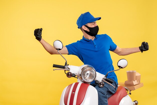 Front view young male courier in blue uniform on yellow background