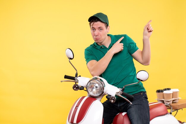 Front view young male courier in green uniform on bike yellow 