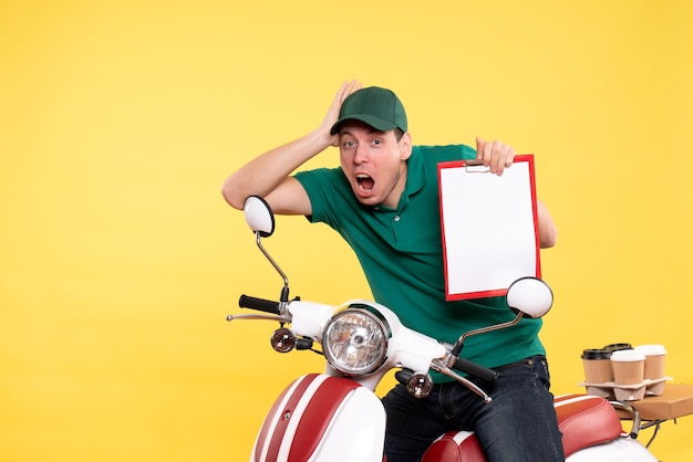 黄色のファイル ノートを保持している緑の制服を着た若い男性宅配便の正面図
