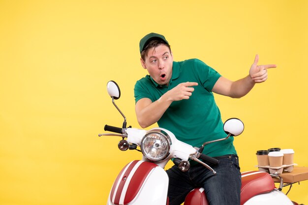 Front view young male courier in green uniform on a yellow 