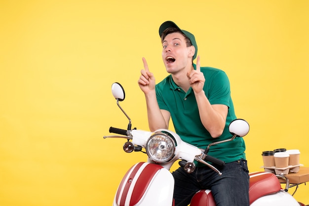 Front view young male courier in green uniform on yellow 