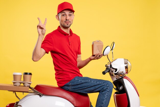 Front view young male courier in red uniform on a yellow background