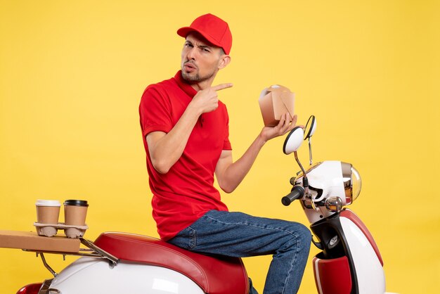 Front view young male courier in red uniform on yellow background