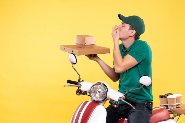 Front view young male courier in uniform holding food packages on yellow 