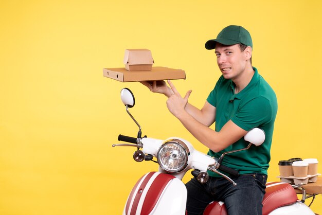 Free photo front view young male courier in uniform holding food packages on yellow