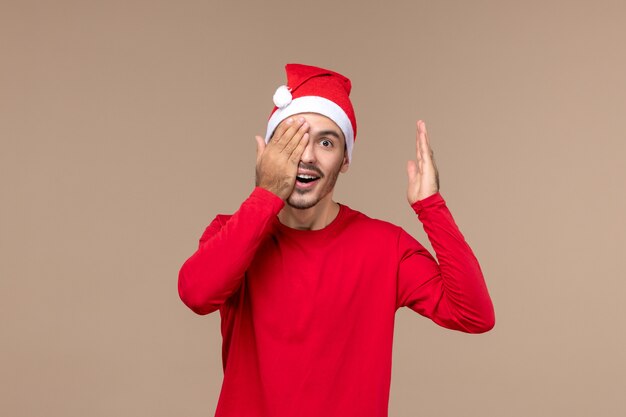 Front view young male covering half of his face on brown background emotion holiday male