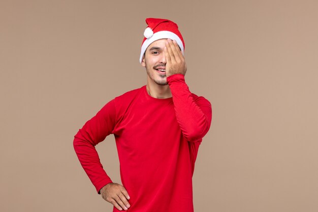 Front view young male covering half of his face on brown background emotions holiday male