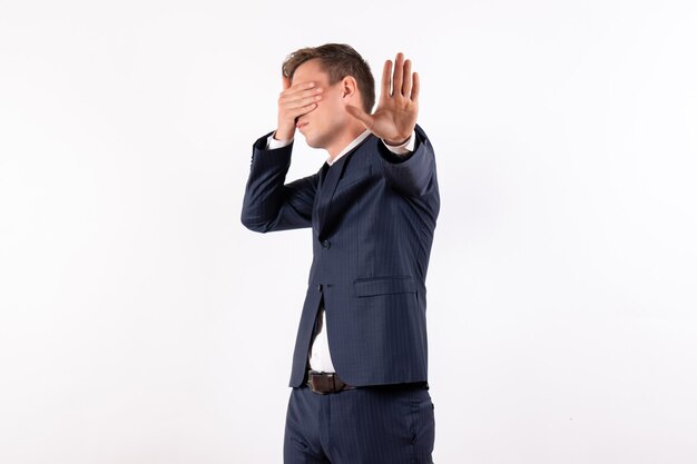 Front view young male covering his face in classic strict suit on the white background emotions human fashion model suit male