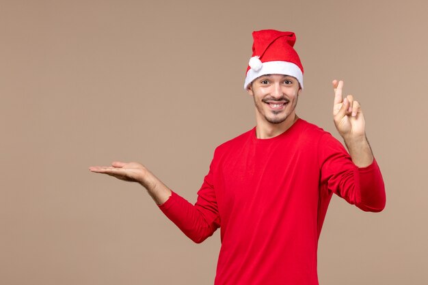 Front view young male crossing his fingers on brown background male color emotion holiday