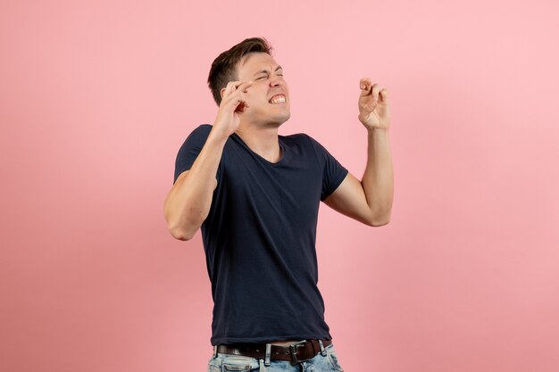 Front view young male in dark-blue shirt crossing his fingers on pink background male emotion human model color man