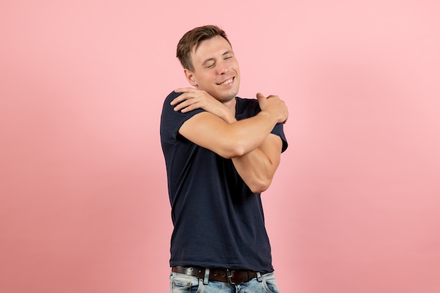 Free photo front view young male in dark-blue shirt hugging himself on pink background male human model color emotion man