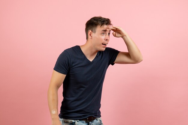 Вид спереди молодой мужчина в темно-синей рубашке, глядя вдаль на розовом фоне мужчина человеческий цвет модель человека эмоции