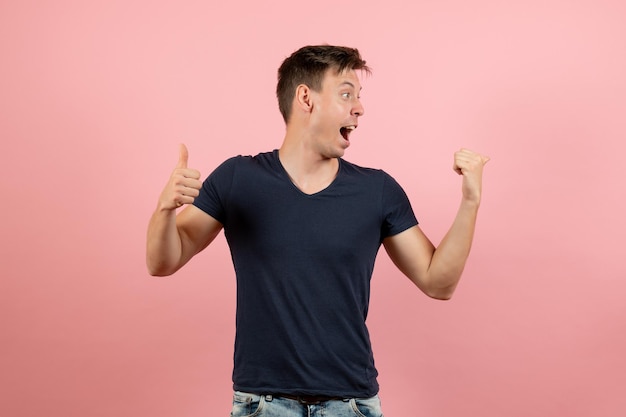 Front view young male in dark-blue shirt posing on light pink background