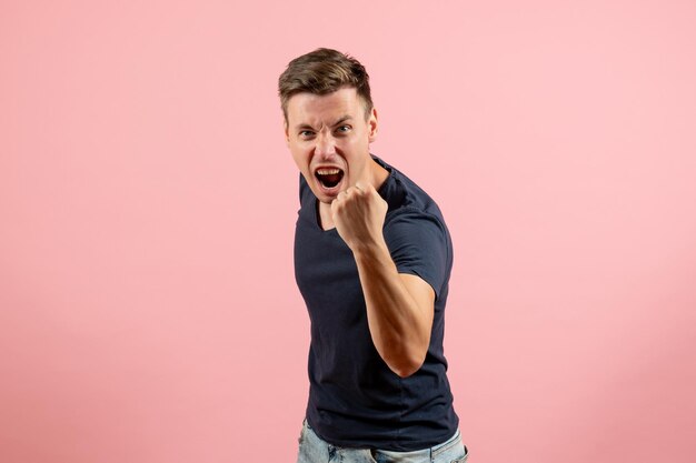 Front view young male in dark-blue shirt posing on a pink background