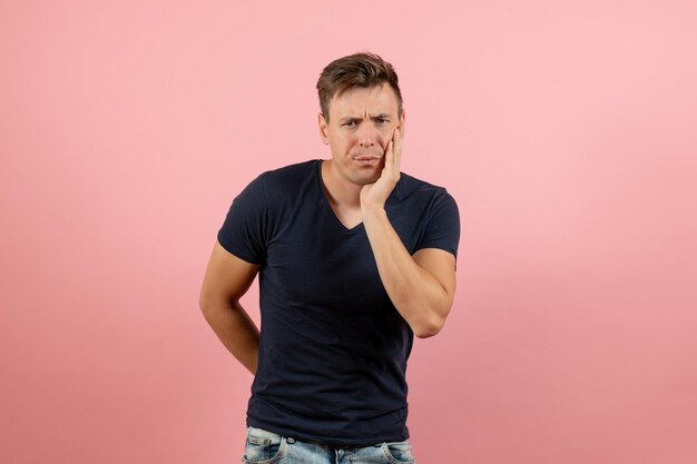 Front view young male in dark-blue shirt posing on pink background