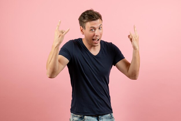 Front view young male in dark-blue shirt posing on pink background