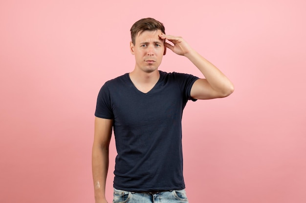 Front view young male in dark-blue shirt posing on pink background