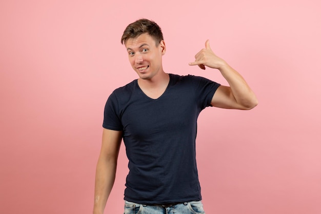 Front view young male in dark-blue t-shirt posing on pink background