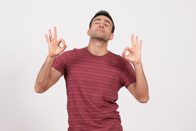 Front view young male in dark-red t-shirt standing and posing on white background