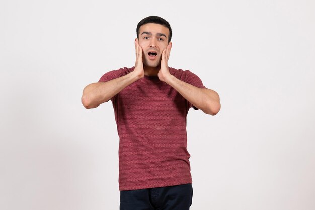 Front view young male in dark-red t-shirt standing and posing on white background