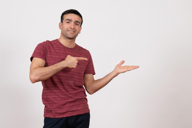 Front view young male in dark-red t-shirt standing and smiling on white background