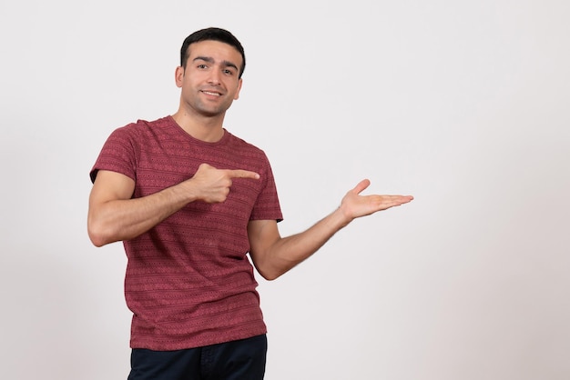 Front view young male in dark-red t-shirt standing and smiling on white background